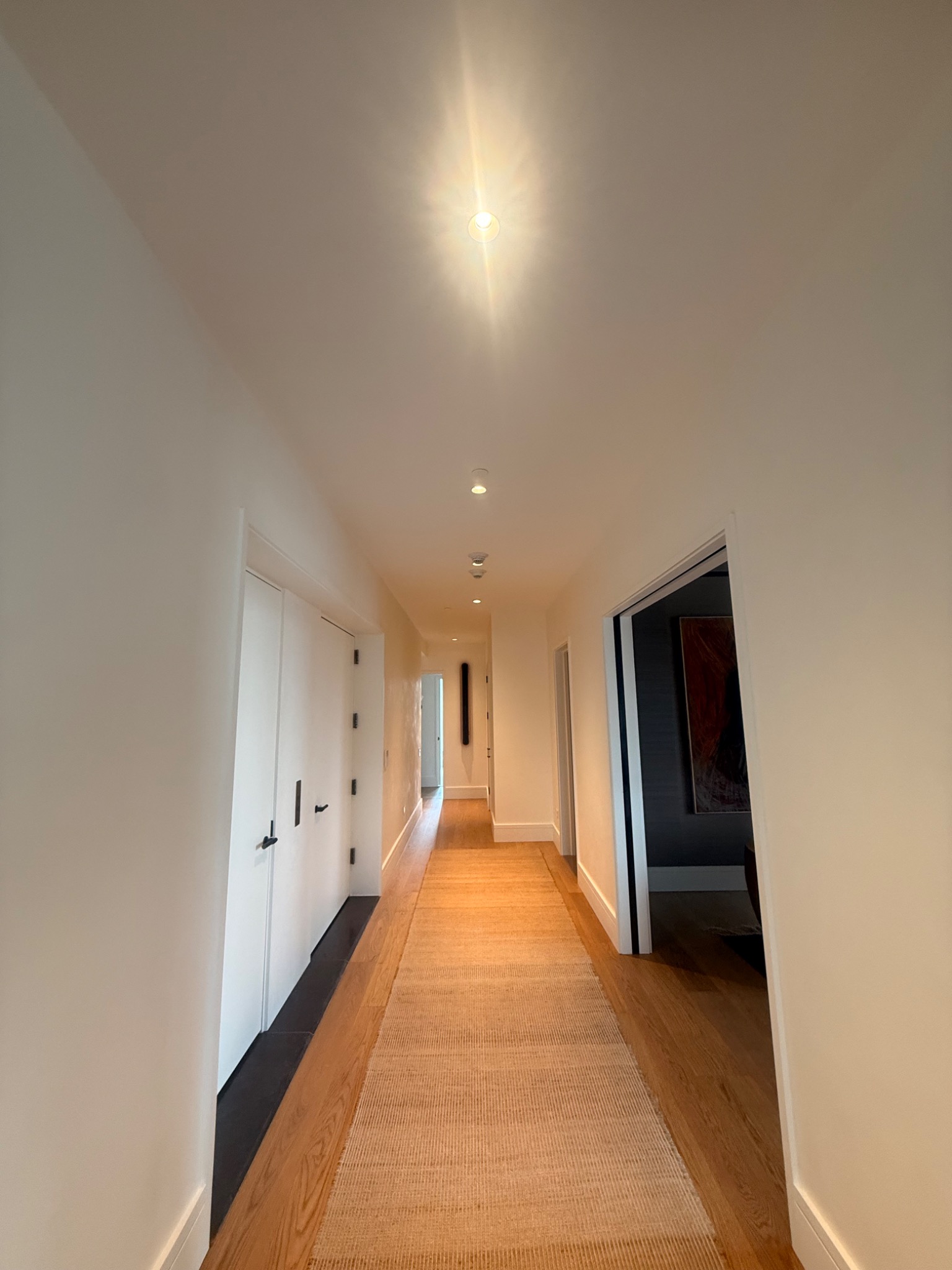 Finished residential hallway with recessed lighting and wood flooring